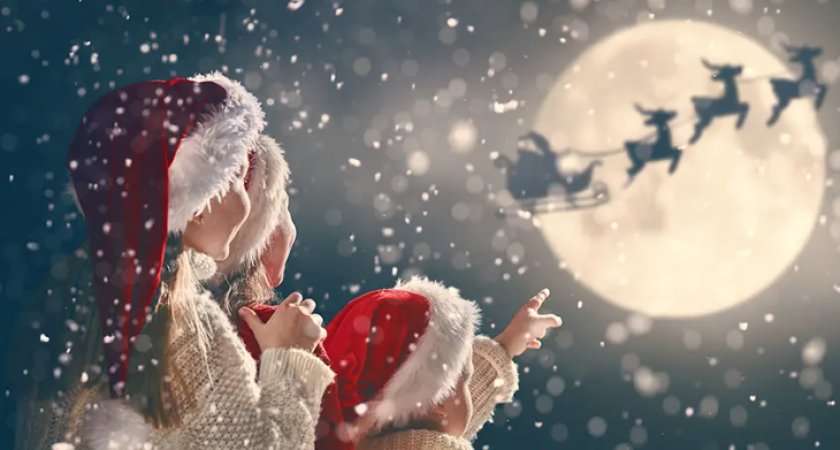 Bambini guardano Babbo Natale volare sulla luna in una notte nevosa.