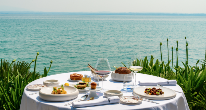 Pranzo elegante con vista mare, piatti raffinati e vino.